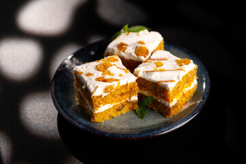 Carrot dessert cake on a plate on a black background.
