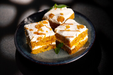 Carrot dessert cake on a plate on a black background.