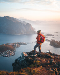 A beautiful girl standing on the top of the mountain Reinebringen, overlooking a Norwegian fjord in...