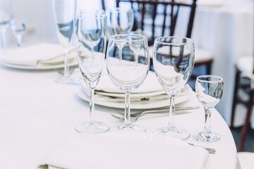 Fancy table set for dinner with napkin glasses in restaurant, luxury interior background. Wedding elegant banquet decoration and items for food arranged by catering service on white tablecloth table.