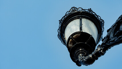 Old-style street lamp set against a blue sky