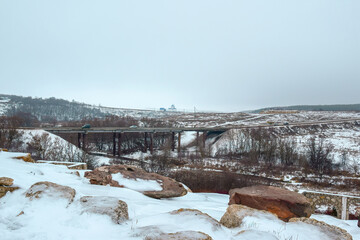 Winter landscape with boulders and a bridge over the river