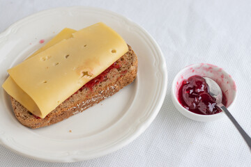 Bread with a slice of cheese and jam on white background