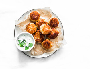 Canned tuna potato fish balls with greek yogurt cilantro sauce on light background, top view