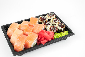 take away sushi in plastic containers, philadelphia rolls and unagi maki, soy sauce, pink ginger, wasabi, sushi delivery concept