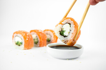 take philadelphia maki rolls with bamboo chopstick on white background