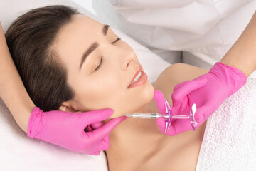 Cosmetologist makes rejuvenating anti wrinkle injections on the face of a beautiful woman. Female...