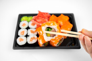 take away sushi rolls in plastic container, california, salmon maki roll, pink ginger, wasabi. sushi delivery concept