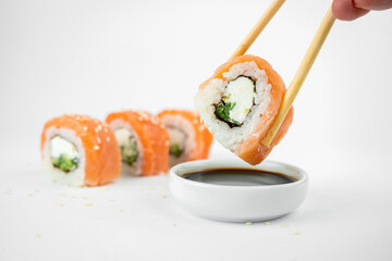 take philadelphia maki rolls with bamboo chopstick on white background