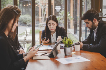 Business professional people group, team of young asian,caucasian working and communicating, analyzing data,discussing, using mobile phone to explain about new project with colleagues in workplace.