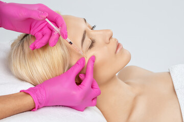 Cosmetologist makes rejuvenating anti wrinkle injections on the face of a beautiful woman. Female...
