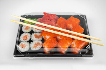 take away sushi rolls in plastic container, california, salmon maki roll, pink ginger, wasabi. sushi delivery concept