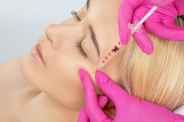 Cosmetologist makes rejuvenating anti wrinkle injections on the face of a beautiful woman. Female...