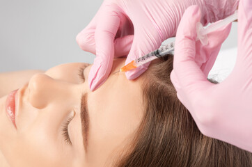 Cosmetologist makes rejuvenating anti wrinkle injections on the face of a beautiful woman. Female...