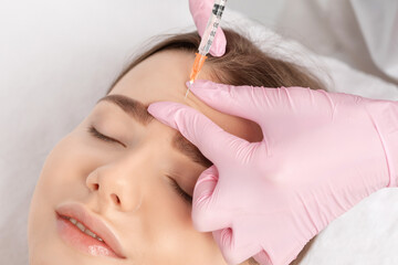 Cosmetologist makes rejuvenating anti wrinkle injections on the face of a beautiful woman. Female...