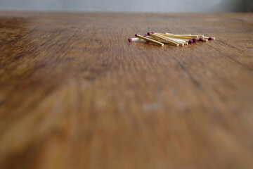 Pile of matches on an old wooden table. Matches in focus. Unexpected angle. Copy space.