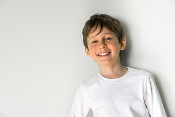 Portrait of smiling 8-year-old boy  in a white t-shirt  with copy space