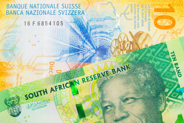 A macro image of a shiny, green 10 rand bill from South Africa paired up with a yellow Swiss ten franc bill.  Shot close up in macro.