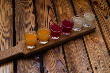 A set of colorful alcoholic tinctures on berries and fruits on a wooden background