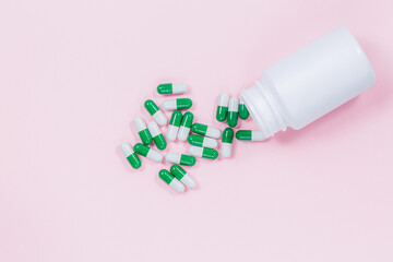 Yogurt capsules in a glass bottle on light pink background with copy space for your text. White probiotics capsules in pink background. Template medical blog social media.