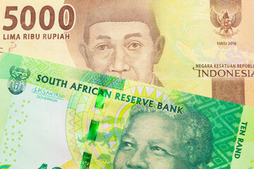 A macro image of a shiny, green 10 rand bill from South Africa paired up with a orange five thousand Indonesian rupiah note.  Shot close up in macro.