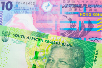 A macro image of a shiny, green 10 rand bill from South Africa paired up with a pink and purple, plastic ten dollar bill from Hong Kong.  Shot close up in macro.