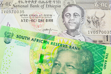 A macro image of a shiny, green 10 rand bill from South Africa paired up with a grey Ethiopian one birr bill.  Shot close up in macro.