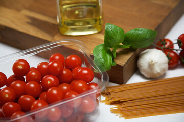 Close up of cherry tomatoes, with basil, garlic, olive oil and spaghetti