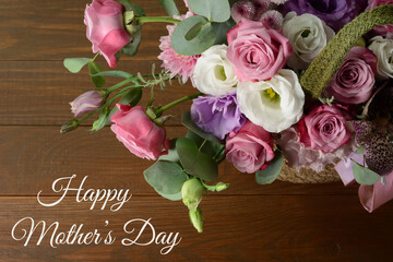 Mothers day card. Bouquet of pink roses in basket on wooden background closeup