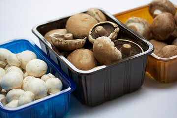 Assorted  raw mushrooms in containers, chestnut, closed cup and button on a white background