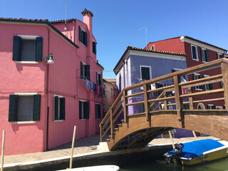 Fototapeta na wymiar Burano canal natural color pink and lavender buildings and footbridge