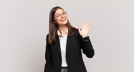 young business woman smiling happily and cheerfully, waving hand, welcoming and greeting you, or saying goodbye © kues1
