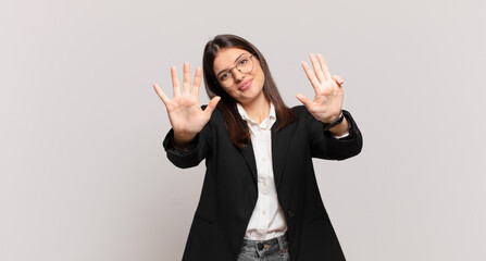 young business woman smiling and looking friendly, showing number nine or ninth with hand forward,...