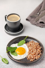 Eggs, buckwheat and spinach on a plate, coffee in a cup. Healthy breakfast.