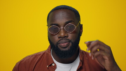 Portrait of african handsome man sending air kiss on yellow background.