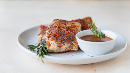 Fried turkey or chicken breast served with orange sauce and rosemary on a plate, light concrete background. Healthy food.