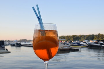 Aperol spritz in a glass with leg and with two blue straws