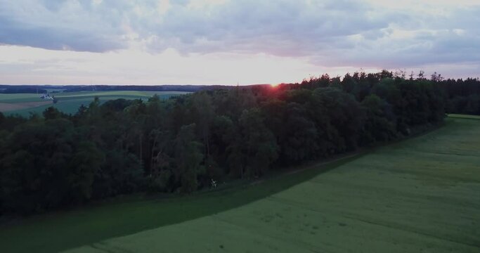 Ascending aerial view from green field revealing gorgeous Sunset, Essenbach, Bavaria