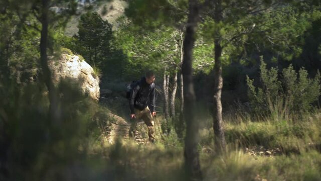 Male photographer hiking through mountainside forest