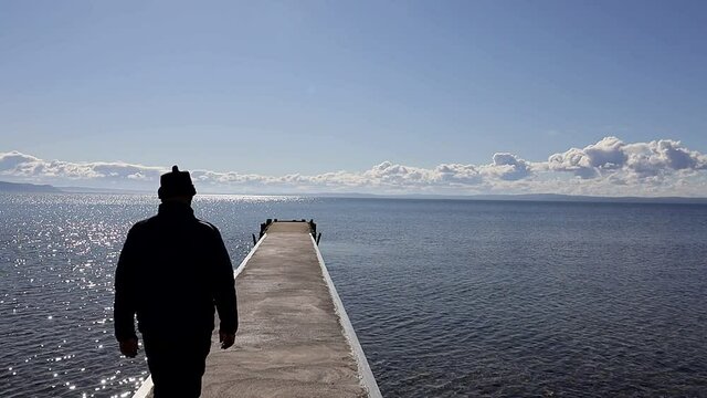 Visingso, Sweden A man walks out on a dock in Lake Vattern on a sunny day. 