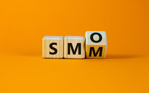 SMM vs SMO symbol. Turned a cube and changed words 'SMM, social media marketing' to 'SMO, social media optimization'. Business, SMM vs SMO concept. Beautiful orange background, copy space.