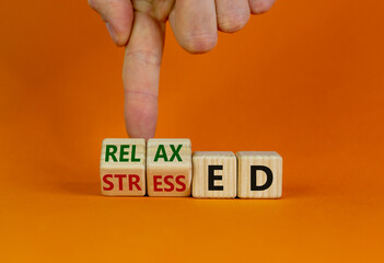 Stressed or relaxed symbol. Businessman turns cubes and changes the word 'stressed' to 'relaxed'. Beautiful orange background. Psychological, business and stressed or relaxed concept. Copy space.