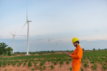 Silhouette of man engineer working and holding the report at wind turbine farm Power Generator Station on mountain,Thailand people