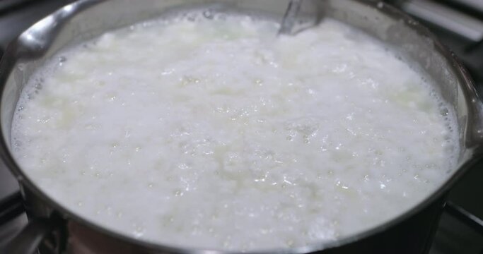 Home made cottage cheese or curd cheese. Pan with milk stands on the kitchen stove. Manufacture of cheese and desserts at home and restaurant or cafe. Cooking healthy food at home. Fermented food.