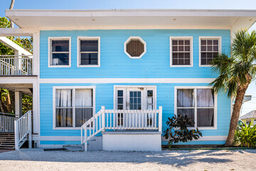 Colorful single family blue turquoise teal and white bungalow home house by beach with palm trees...