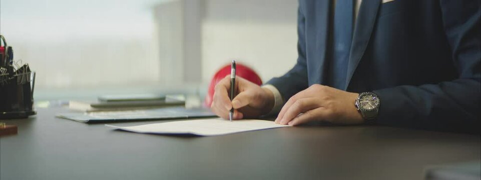 A Man in a suit signing a Contract in a modern office.