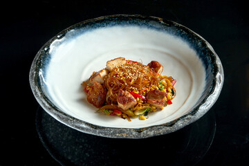 Sweet and sour glass noodles with pork, vegetables and onions, served in a white bowl. Wok noodles. Isolated over black background. Street thai food