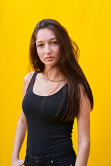 Vertical photo of a caucasian woman touching her hair and looking at camera, on yellow plain background