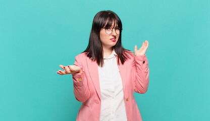 young business woman shrugging with a dumb, crazy, confused, puzzled expression, feeling annoyed...