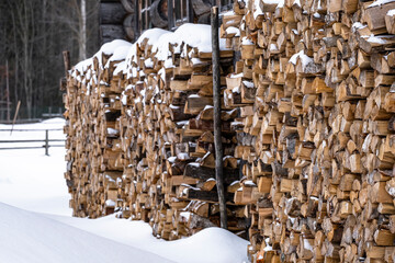 a woodpile with firewood is next to the house to quickly heat a log village house built in the 19th century